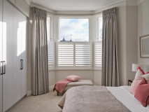 Bedroom curtains in front of plantation shutters
