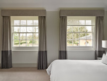 Twin curtains hanging from upholstered pelmets